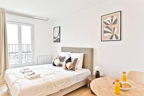 une chambre blanche avec un grand lit et une table dans l'établissement Studio charmant tout équipé Paris Montreuil - III, à Montreuil