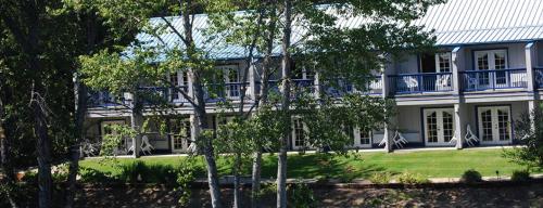 Shady CoveにあるEdgewater Inn Shady Coveの青いバルコニーと木々が備わる白い大きな建物