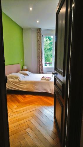 a bedroom with a bed with green walls and a window at Chambres d'hôtes au Château Léon in Morvillars