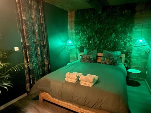 - une chambre verte avec un lit et des serviettes dans l'établissement Jungle Suite - Immersion Tropicale, à Cambrai