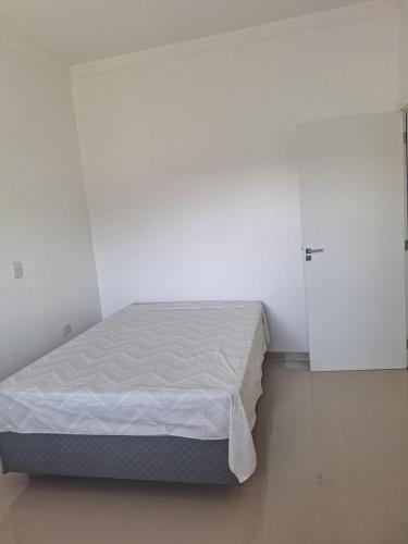 a white room with a bed and a door at Casa Bourbon in Foz do Iguaçu