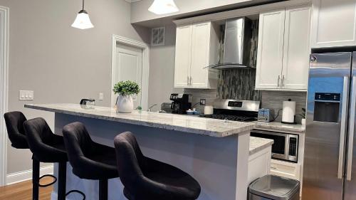a kitchen with white cabinets and a counter with bar stools at Private Balcony 1 Garage Parking Sleeps 6 in Chicago