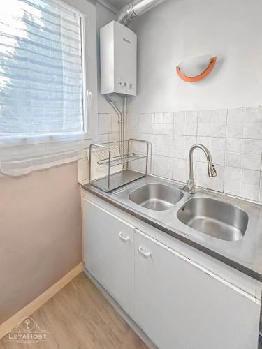 une cuisine blanche avec un évier et une fenêtre dans l'établissement Appartement moderne avec Wi-Fi et Balcon, à Choisy-le-Roi