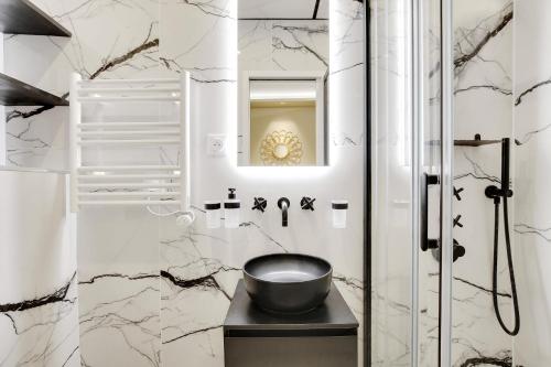 une salle de bain avec des murs en marbre blanc et un bol sur une table dans l'établissement Pick A Flat's apartment in Champs-Elysées - Rue Marbeuf, à Paris