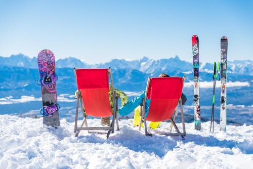 two chairs in the snow with skis and snowboards at Appartement Seeleben in Bodensdorf