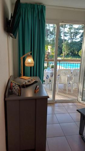 a room with a table with a lamp and a balcony at T2 Turquoise Ondres plage avec piscine et tennis in Ondres