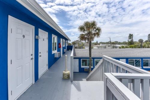 a blue house with a white door and a palm tree at Cozy Studio Suite Near Beach W Kitchenette #11 in Daytona Beach Shores