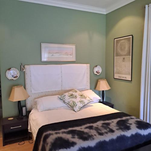 a bedroom with a bed with a white headboard and two lamps at Corgi Cottage in Stanford