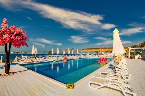 a swimming pool with white chairs and umbrellas at Porto Marina Resort & Spa Al Alamein in El Alamein