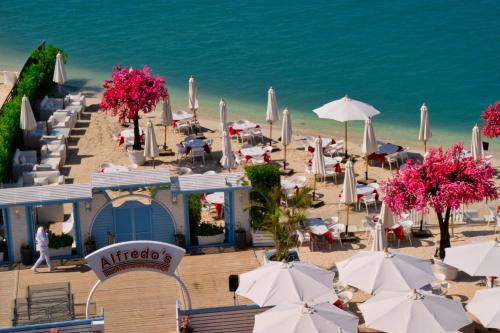 a beach with tables and umbrellas and the ocean at Porto Marina Resort & Spa Al Alamein in El Alamein
