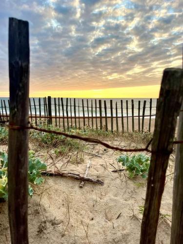 a fence on the beach with the ocean in the background at T2 Turquoise Ondres plage avec piscine et tennis in Ondres