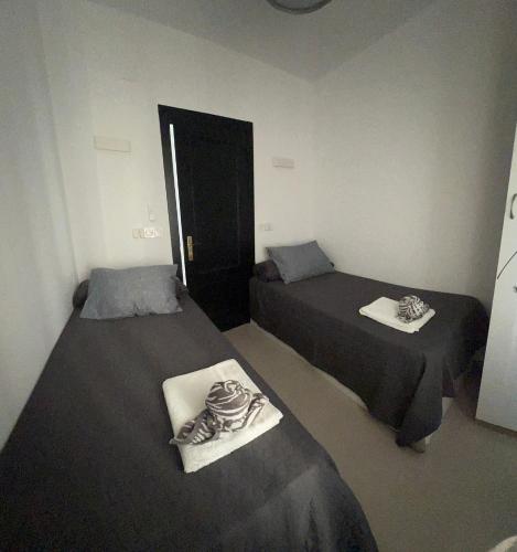 a room with two beds and a door in it at Apartamento Royal Gines I a 10 minutos de Sevilla in Ginés