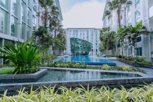 a view of a building with a swimming pool and palm trees at City Center Residence KR in Pattaya Central
