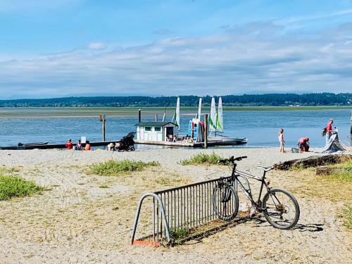 a bike parked on a beach with boats in the water at Scorpion Hiuse Langley ROOM B in Langley