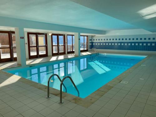 une grande piscine avec de l'eau bleue dans un immeuble dans l'établissement Chez Cathy, à Orcières