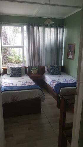 two beds in a room with a window at Porta Salutis in Port St Johns