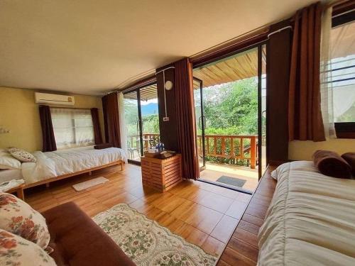 a living room with a couch and a large window at ห้องลานเคียงดาว บ้านสวนสราญชล in Ban Plai Nam (2)