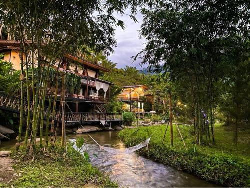 a house with a bridge over a river next to a riverurrency sidx sidx sidx at ห้องลานเคียงดาว บ้านสวนสราญชล in Ban Plai Nam (2)