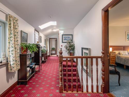 a hallway with a staircase with a red carpet at Large 5 bedroom home to sleep 10 people with wonderful sea views in Kenmare