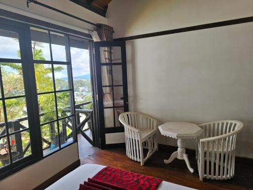 a room with two chairs and a table and windows at Chez Allen in Nuwara Eliya