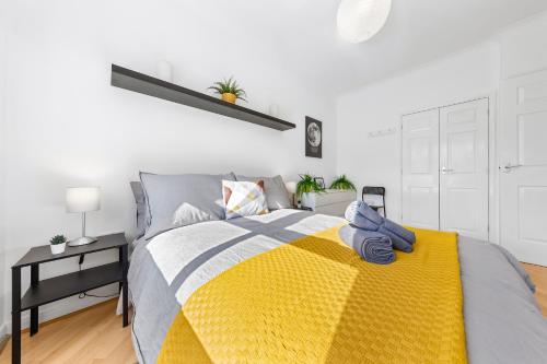 a bedroom with a bed with a yellow blanket at Cozylease 3 Bedroom Canary Wharf Family,Workcation, Fast WiFi, Workspace,1 stop to City in London