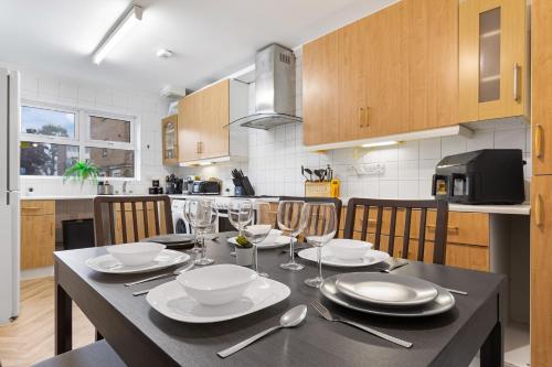 a kitchen with a table with plates and wine glasses at Cozylease 3 Bedroom Canary Wharf Family,Workcation, Fast WiFi, Workspace,1 stop to City in London