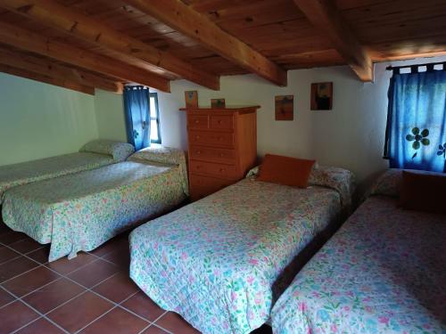 three beds in a room with blue curtains at Huerta Rocio in Linares de la Sierra