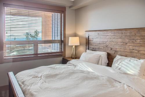 a bedroom with a large white bed and a window at Stonegate Resort Unit B302 in Big White