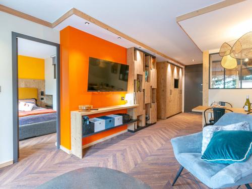 - un salon avec un mur d'accent orange et un lit dans l'établissement Appartement rénové avec wifi et animaux acceptés au cœur de Val-d'Isère - FR-1-694-366, à Val dʼIsère