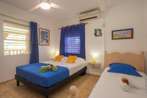 two beds in a bedroom with blue and white at Villa Cocotier in Sainte-Anne