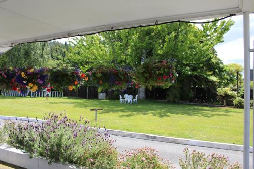 a garden with flowers hanging from a white canopy at Fairy Springs Motel in Rotorua