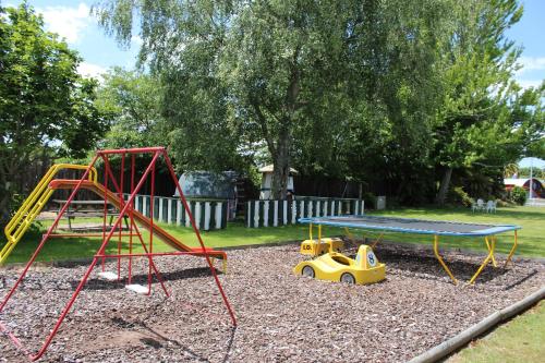 a playground with a table and a swing set at Fairy Springs Motel in Rotorua