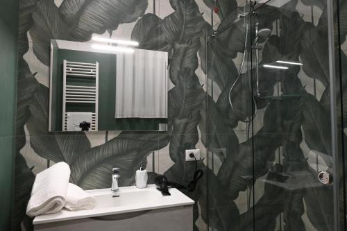 a bathroom with a sink and a shower with a leaf wallpaper at Pane Amore e B&B in Pompei