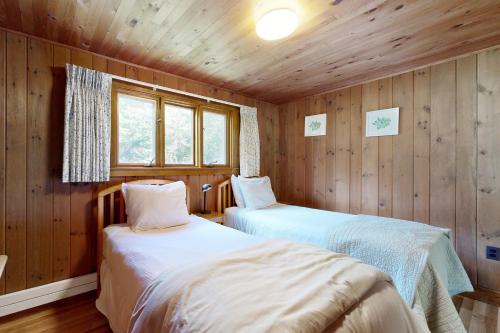 zwei Betten in einem Zimmer mit Holzwänden in der Unterkunft Reed Shore Cottage in Bass Harbor