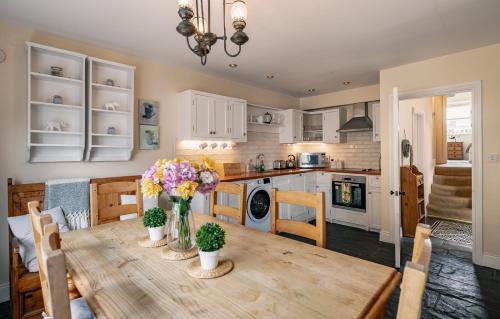 a kitchen and dining room with a wooden table with flowers at 3 bedroom pet friendly home in the heart of Kenmare town in Kenmare