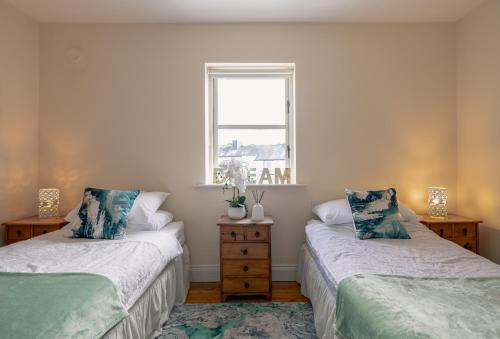 two beds in a room with a window at 3 bedroom pet friendly home in the heart of Kenmare town in Kenmare