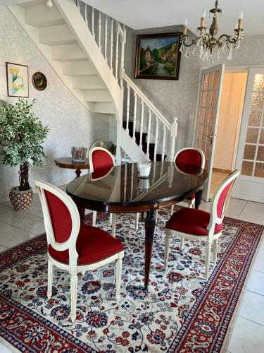une salle à manger avec une table en verre et des chaises rouges dans l'établissement Maison de la Métairie, à Les Sables-dʼOlonne