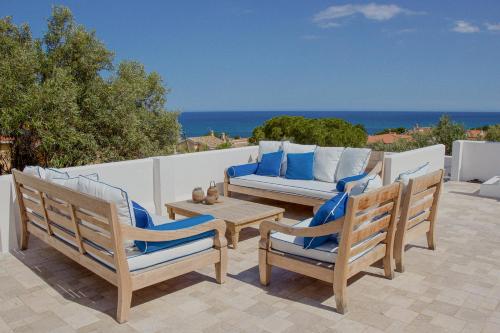 deux chaises et une table sur une terrasse avec l'océan dans l'établissement Il Polpo Nero l Villa Vue Mer, Piscine, Rooftop & 2 Vespa, à Porto Columbu - Perdʼe Sali