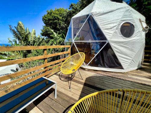 a yurt with two chairs and a bench on a deck at Bubble Dome Village in Saint-Joseph
