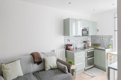 Il comprend un salon avec un canapé gris et une cuisine. dans l'établissement AI- Cocon Parisien près de la Cité des Sciences, à Paris