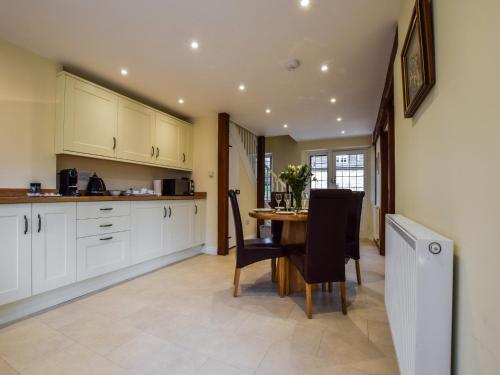 a kitchen with white cabinets and a table and chairs at Queen Mary in Winchcombe