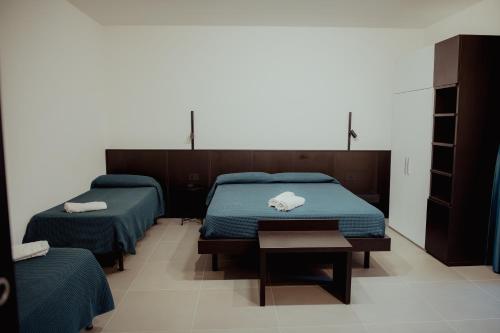 a bedroom with two beds with blue sheets and a table at VicoLetto Bed and Breakfast in Laino Borgo