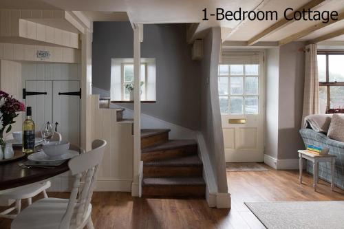a living room with a staircase with a table and chairs at Hill End Cottages in Warslow