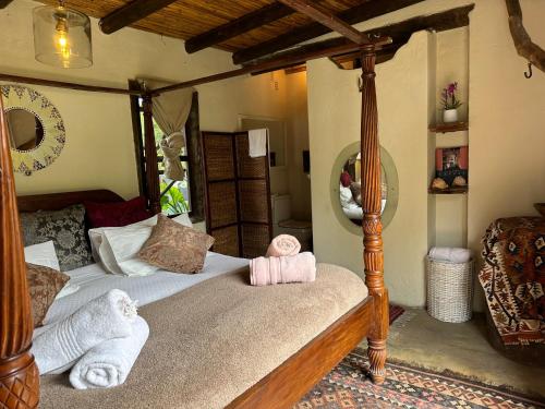 a bedroom with a canopy bed with towels on it at Stormsriver Backpackers Dijembe in Stormsrivier
