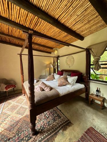a bedroom with a canopy bed in a room at Stormsriver Backpackers Dijembe in Stormsrivier