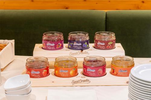 four jars of jam on a wooden tray with plates at Hotel Relais Orsingher in Fiera di Primiero