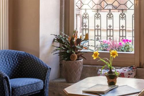 a table and a chair and a window with flowers at Hotel Relais Orsingher in Fiera di Primiero