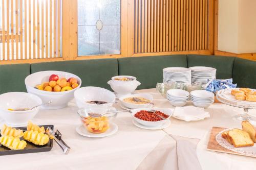 a table with bowls and plates of food on it at Hotel Relais Orsingher in Fiera di Primiero