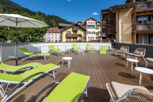a deck with chairs and tables and an umbrella at Hotel Relais Orsingher in Fiera di Primiero