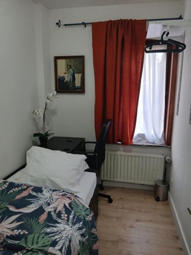 a bedroom with a bed and a desk and a window at Kamertje in Asse